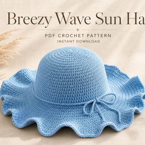 Puede incluir: Un sombrero de sol de ganchillo azul claro con ala ancha y ondulada y un fino lazo decorativo alrededor de la copa. El texto sobre el sombrero dice Breezy Wave Sun Hat, PDF CROCHET PATTERN, INSTANT DOWNLOAD. Presenta un tejido denso y uniforme.
