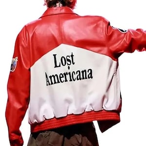 May include: A red and white leather jacket featuring a large white panel on the back with the black text Lost Americana printed in the center. The jacket has a collared neckline, long sleeves with circular patches, and a ribbed red hem at the waist.