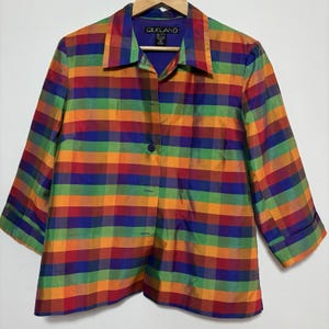 May include: A colorful, plaid silk jacket with three-quarter sleeves. The jacket features a button-down front and a collar. The color scheme includes red, orange, yellow, green, blue, and purple. The label reads "SILKLAND".