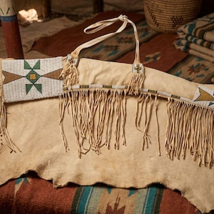 Può includere: Una borsa in pelle color cuoio con lunghe frange e intricate perline con motivi geometrici bianchi, verdi e marroni. La borsa include una tracolla ed è realizzata in morbida pelle dai toni naturali con cuciture a vista.