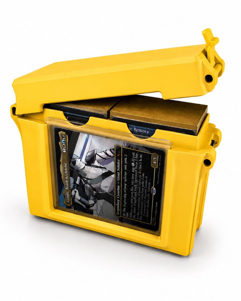 May include: A bright yellow plastic storage case for trading cards with a hinged lid. The front features a clear display window holding a single card with a black border and a character illustration. Inside, two stacks of cards are visible.