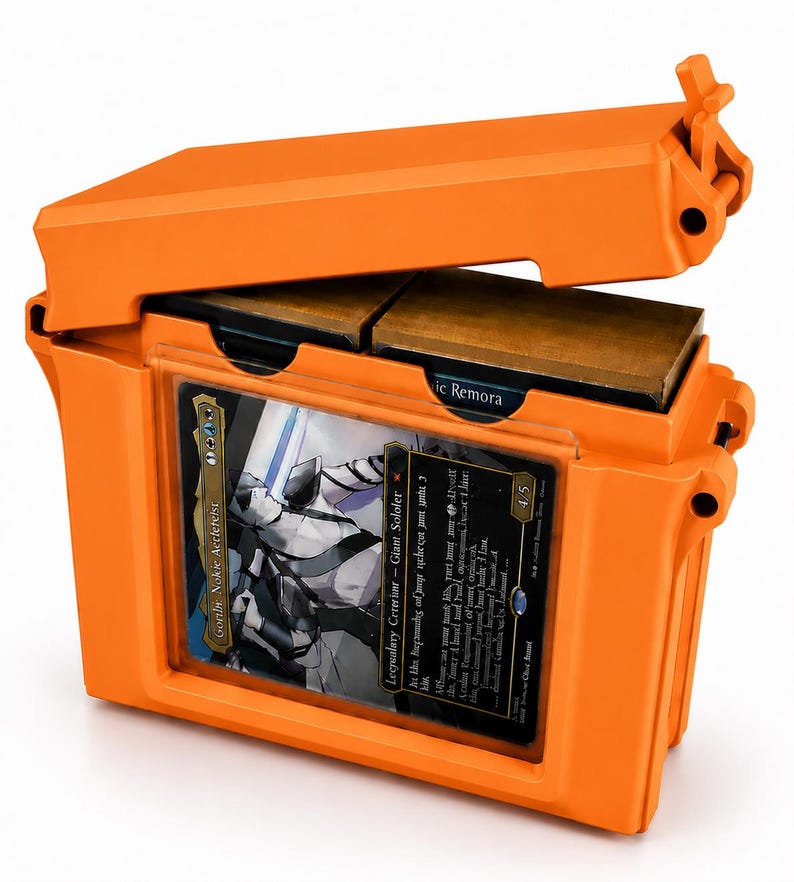 May include: A bright orange, rectangular hard-shell storage case with a hinged lid. The front features a clear window displaying a trading card titled Gorlin, Nokie Aetereist. Inside, two dark brown card decks are visible through the open top.