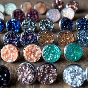 May include: Assortment of colorful sparkly stud earrings with a variety of colors including blue, green, purple, pink, and gold. The earrings are set in silver.