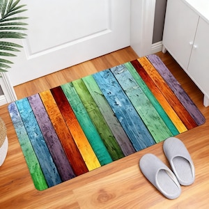 May include: A rectangular floor mat featuring a printed pattern of vertical wooden planks in a vibrant rainbow color palette, including shades of green, blue, purple, orange, red, and yellow with a weathered, distressed texture throughout.