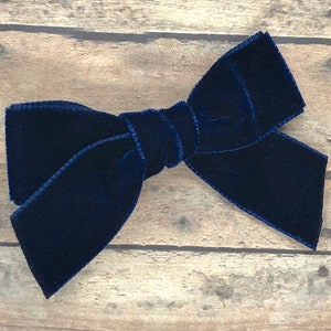 May include: A navy blue velvet bow.