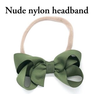 Pode incluir: Uma faixa de cabe&ccedil;a de nylon nude com um grande la&ccedil;o verde. O la&ccedil;o &eacute; feito de um tecido macio e texturizado.