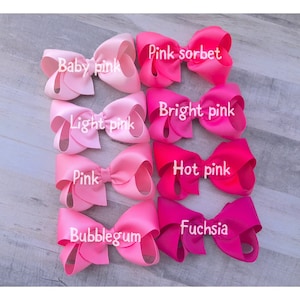 May include: A collection of eight pink hair bows in various shades, including baby pink, light pink, pink, bubblegum, pink sorbet, bright pink, hot pink, and fuchsia. Each bow is labeled with its respective color name in white text.