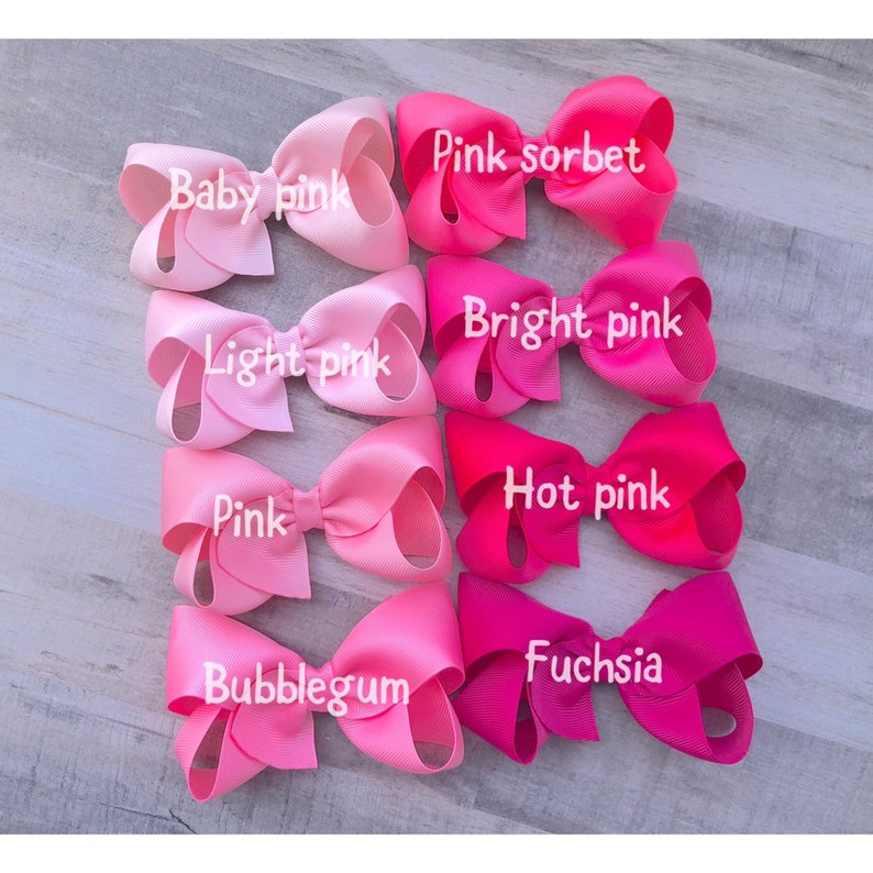 May include: A collection of eight pink hair bows in various shades, including baby pink, light pink, pink, bubblegum, pink sorbet, bright pink, hot pink, and fuchsia. Each bow is labeled with its respective color name in white text.