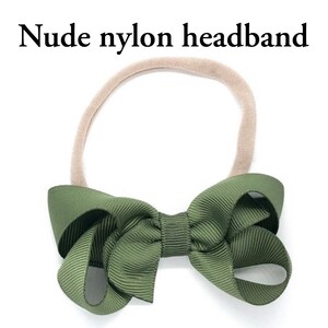 May include: A nude nylon headband with a large green bow. The bow is made of a grosgrain ribbon.