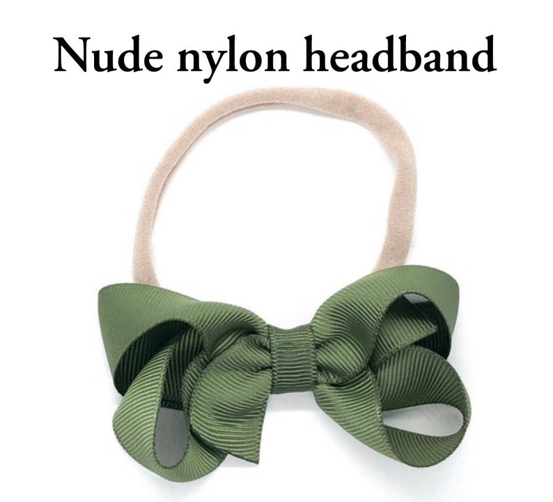May include: A nude nylon headband with a large green bow. The bow is made of a grosgrain ribbon.