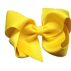 May include: A large yellow hair bow made of grosgrain ribbon.