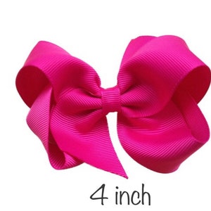K&ouml;nnte beinhalten: Eine leuchtend pinke Haarschleife aus Ripsband. Die Schleife misst 10,16 cm und hat ein klassisches, symmetrisches Design. Die leuchtende Farbe und das strukturierte Band schaffen ein auff&auml;lliges Accessoire.