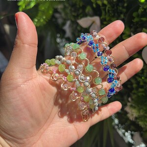 May include: A collection of wire-wrapped bracelets featuring various colorful beads, including green, blue, pink, and clear crystal accents. The text "all the bracelets I made this weekend!" and "Sneak peek" are visible in the image.