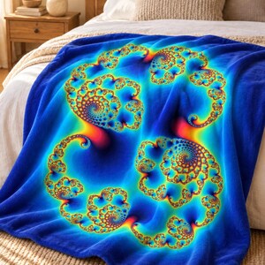May include: A soft plush throw blanket featuring a vibrant, multi-colored fractal spiral pattern. The design displays intricate, repeating swirls in shades of electric blue, bright yellow, orange, and red, set against a deep blue background.