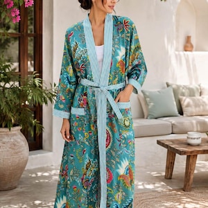 May include: A long-length teal robe featuring a vibrant multi-coloured floral and paisley print. The garment includes a white and teal striped trim along the front opening, cuffs, pockets, and a matching tie belt at the waist for a secure closure.