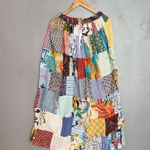 May include: A long, ankle-length skirt featuring a patchwork design composed of various fabric squares in diverse colors and patterns, including floral, striped, and geometric prints. The skirt has an elasticized waistband with a white drawstring.