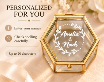 Puede incluir: Un joyero hexagonal de cristal con marco de metal dorado y tapa abatible. La tapa presenta un diseño de corona impreso en blanco con los nombres Amelia & Noah. El texto indica: PERSONALIZED FOR YOU, 1 Enter your names, 2 Check spelling carefully, Up to 20 characters.
