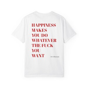 Può includere: Una t-shirt bianca a maniche corte con testo rosso sul retro che recita: HAPPINESS MAKES YOU DO WHATEVER THE FUCK YOU WANT, seguito dal testo grigio più piccolo -It's Blatant. La maglietta ha un girocollo e una vestibilità standard.