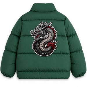 Könnte beinhalten: Eine tannengrüne Steppjacke mit hohem Kragen und horizontalen Steppnähten. Auf der Rückseite befindet sich ein großer, detaillierter Grafikaufnäher eines gewundenen Drachen mit grauen Schuppen, roten Akzenten und scharfen weißen Umrissen.