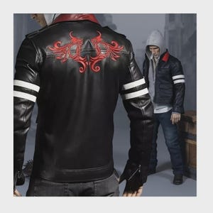 Könnte beinhalten: Eine schwarze Lederjacke mit einem roten gestickten Emblem auf dem Rücken, einem roten Kragen und zwei weißen horizontalen Streifen an jedem Ärmel. Die Jacke ist von hinten zu sehen, mit einer zweiten Ansicht über einem grauen Kapuzenpullover.