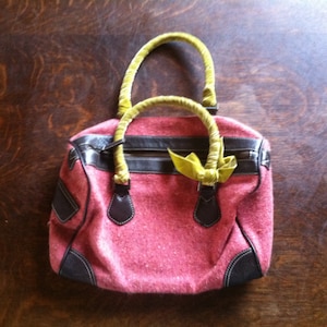 Monedero de tweed rosa con asas de terciopelo verde lima y ribete de cuero marrón oscuro