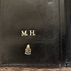 May include: Black leather wallet with gold embossed lettering "M.H." and the logo "CROSS FRANCE".