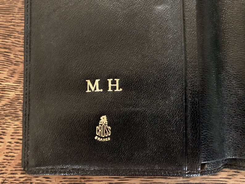 May include: Black leather wallet with gold embossed lettering "M.H." and the logo "CROSS FRANCE".