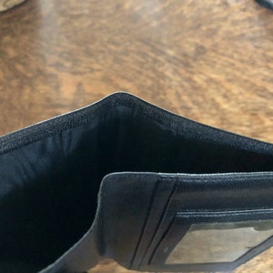 May include: Black leather wallet with a clear plastic window for identification.