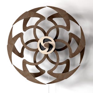 Peut inclure: Une sculpture murale circulaire composée de lames incurvées au motif de grain de bois brun foncé, disposées en un motif floral symétrique et entrelacé. Une pièce centrale circulaire en bois clair avec un détail noir relie les lames.