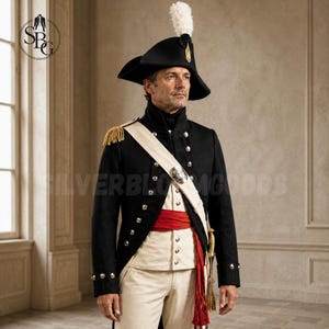 Op de afbeelding: Een zwarte steek met een witte veren pluim, een zwart militair jasje met gouden epauletten en zilveren knopen, een witte sjerp met een zilveren embleem, een rode middelband en een witte broek gedragen door een persoon.