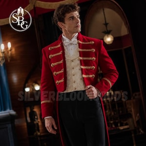 May include: A red tailcoat jacket featuring gold braided cord detailing and gold buttons, worn over a cream-coloured patterned waistcoat with a white dress shirt and a white bow tie, paired with black trousers. The logo SBG is visible in the corner.