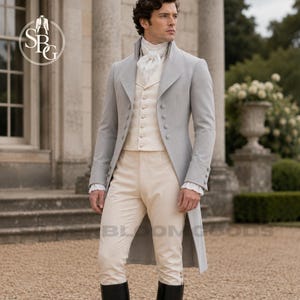 May include: A light grey tailcoat jacket worn over a cream-coloured waistcoat and matching cream trousers. The ensemble includes a white ruffled cravat at the neck and white shirt cuffs. The jacket features a row of buttons and long back panels.