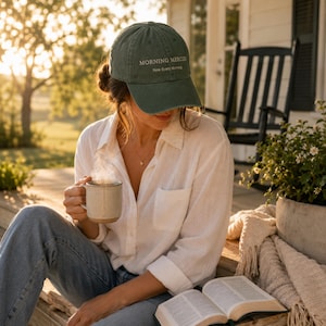 Puede incluir: Una gorra de béisbol de color verde oliva oscuro con el texto bordado MORNING MERCIES New Every Morning en hilo blanco. La gorra tiene una visera curva y una corona estructurada, diseñada con una construcción clásica de seis paneles.