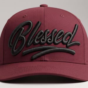 May include: A maroon baseball cap featuring the word Blessed embroidered in raised black lettering across the front. The cap has a structured crown, a curved brim, and a button on top, with a consistent deep red fabric throughout the design.