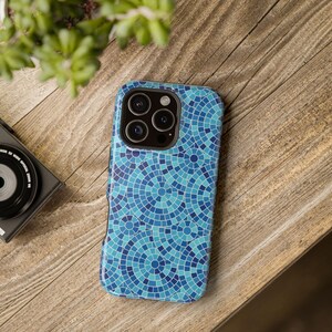 May include: A smartphone case featuring a repeating pattern of concentric circles in various shades of blue and teal, resembling a mosaic tile design. The case has a cutout for a triple-lens camera system on the upper left corner of the back.
