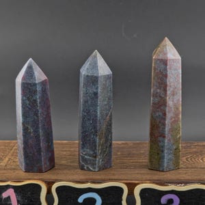 May include: Three polished stone towers with hexagonal bases and pointed tops. The stones feature mottled textures in shades of blue, grey, and reddish-brown. Below each stone is a black chalkboard label with the numbers 1, 2, and 3 written in chalk.