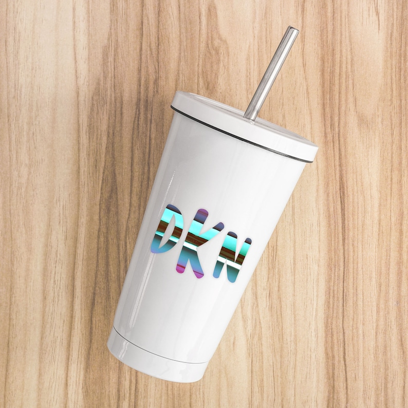 K&ouml;nnte beinhalten: Ein wei&szlig;er Edelstahlbecher mit einem blau, gr&uuml;n, lila und braun gestreiften "DKN"-Design und einem silbernen Strohhalm.