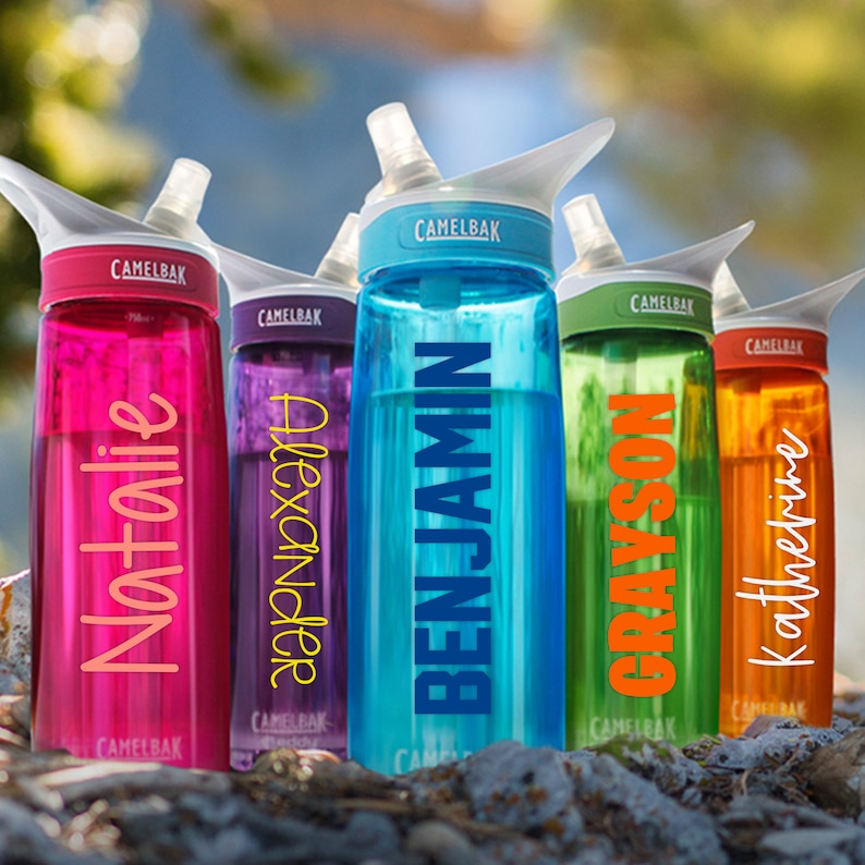 May include: Five personalized water bottles with different names on them. The bottles are all different colors: pink, purple, blue, green, and orange. Each bottle has a clear plastic straw and a flip top lid.