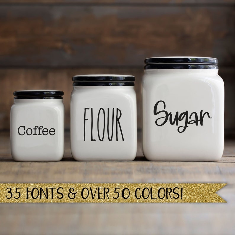 May include: Three white ceramic kitchen canisters with black lids, labeled "Coffee", "Flour", and "Sugar" in black script. A gold banner at the bottom reads "35 FONTS & OVER 50 COLORS!"