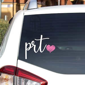 May include: White car window decal with the text "prt" in cursive script followed by a pink heart.