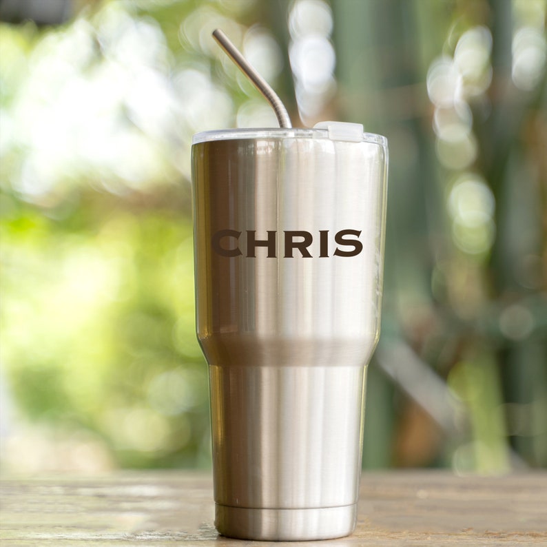 May include: A stainless steel tumbler with a straw and the name "CHRIS" engraved on the side.