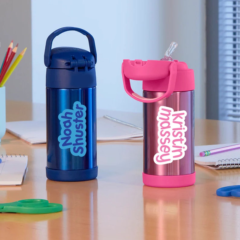 Pu&ograve; includere: Due borracce in acciaio inox con etichette personalizzate colorate. La borraccia blu ha un'etichetta che dice "Noah Shuster" e la borraccia rosa ha un'etichetta che dice "kristin massey".