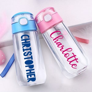 May include: Two clear plastic water bottles with flip top lids. One bottle is blue with the name "CHRISTOPHER" in blue lettering. The other bottle is pink with the name "Charlotte" in pink lettering.