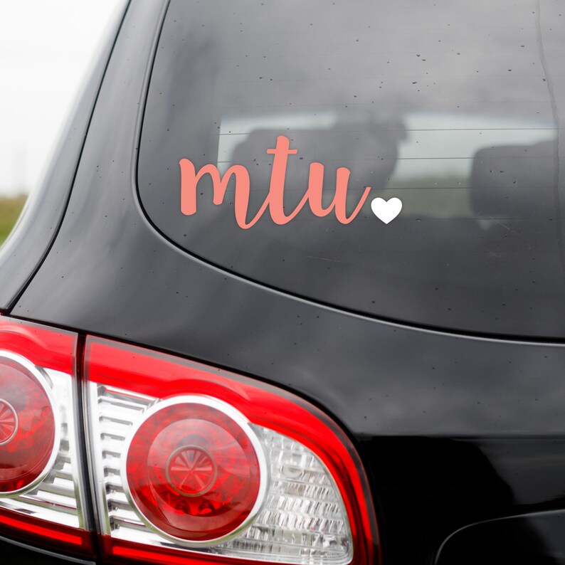 May include: A black car with a pink "MTU" decal and a white heart on the back window.