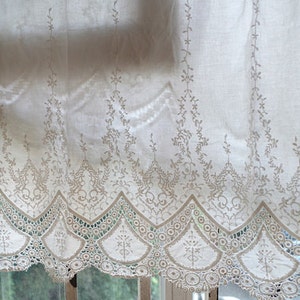 May include: White lace curtain with a delicate floral pattern and scalloped edge.