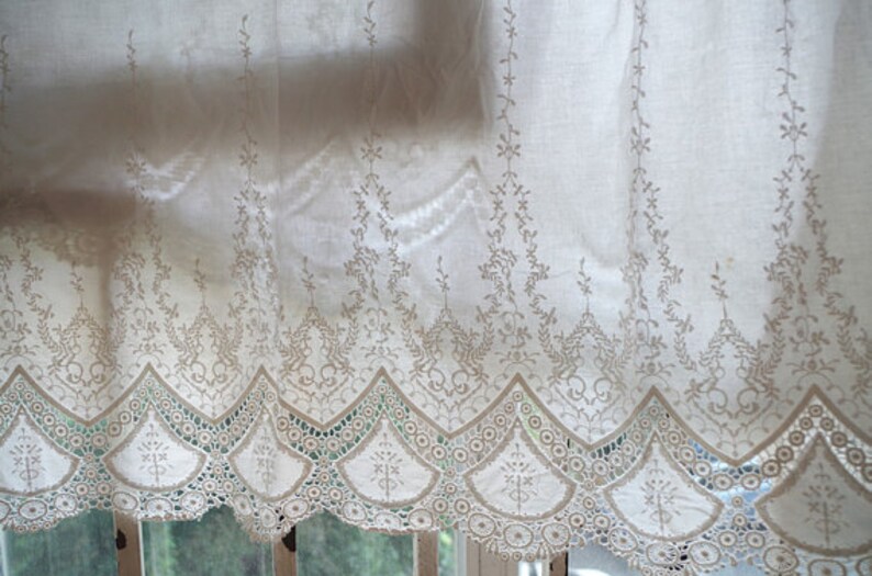 May include: White lace curtain with a delicate floral pattern and scalloped edge.