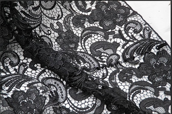 Black lace texture with flowers on a white background.Background of black  lace with a flower pattern on a white background. Black guipure. Black  fabric with an ornament. Stock Photo
