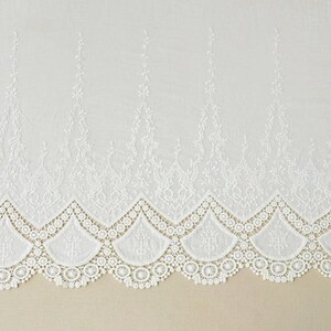 May include: White cotton lace trim with a scalloped edge and delicate floral embroidery. The lace has a repeating pattern of small flowers and leaves.