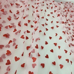 May include: Pink tulle fabric with a red glitter heart pattern.