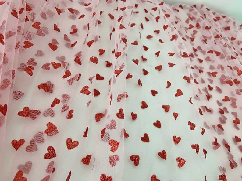 May include: Pink tulle fabric with a red glitter heart pattern.